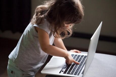 Curious smart little girl typing on laptop alone, clever cute child using computer online without permission, forbidden internet content parental protection, pc control and security for kid concept