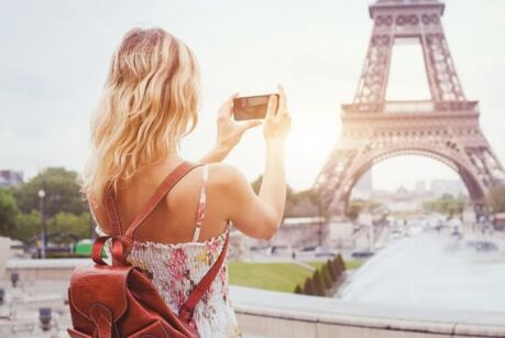 tourist in Paris visiting landmark Eiffel tower, sightseeing in France, woman taking photo on mobile phone