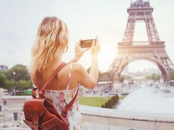 tourist in Paris visiting landmark Eiffel tower, sightseeing in France, woman taking photo on mobile phone