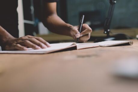 Checklist Writing Notice Remember Planning assessment Concept,home office desk background,hand holding pen and writing note on wood table.