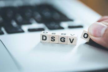 DSGVO: Wooden cubes with letters “DSGVO” lying on a laptop. Datenschutzgrundverordnung.