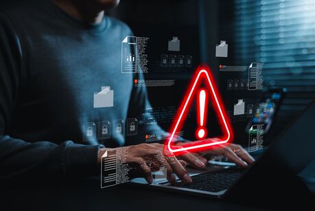 Rotes Warnsymbol und digitale Schloss-Icons über einer Person am Laptop, symbolisch für eine Datenpanne