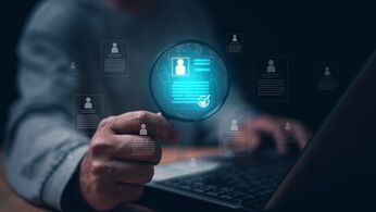 Hand hält eine Lupe über ein digitales Personenprofil mit Häkchen, umgeben von Profil-Icons vor einem Laptop – Symbol für die Suche nach personenbezogenen Daten